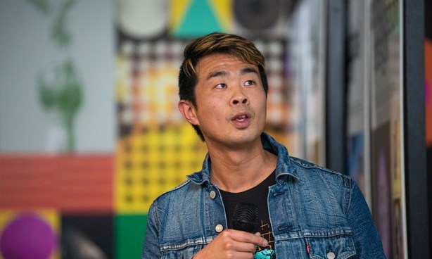 Headshot of artist Xavier Ho in a denim jacket and black t-shirt