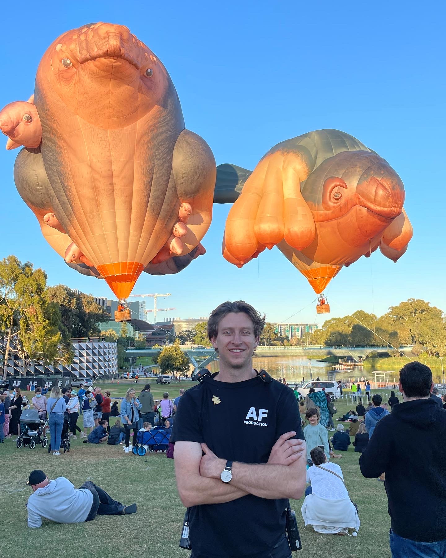 Connor Jolly standing in a park with animal-shaped hot air balloons floating behind him