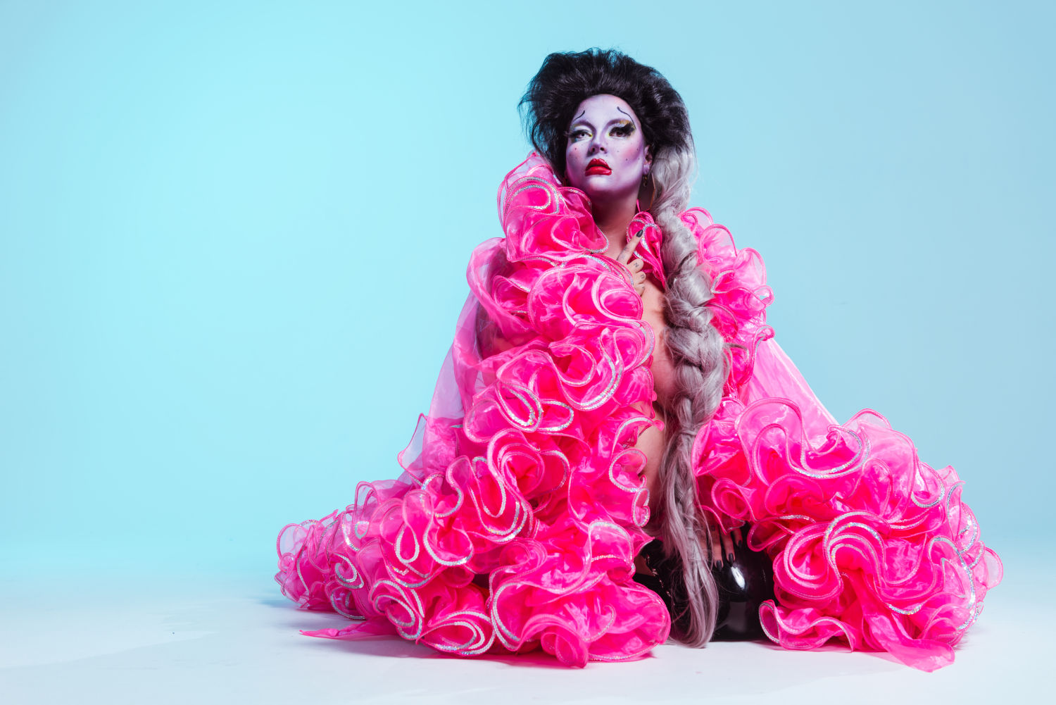 Woman with black hair/wig, fully encompassed in a frilly pink dress