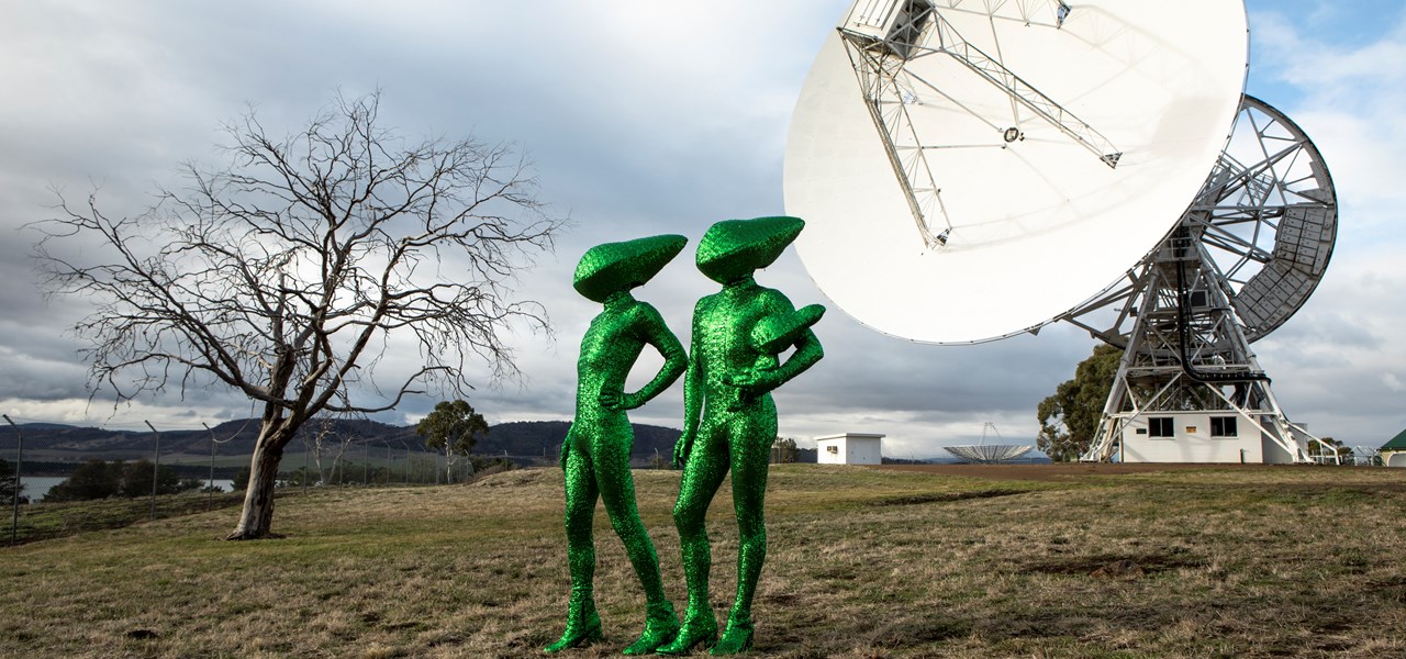 The Huxleys dressed as green extra-terrestrials with a radio telescope in the background