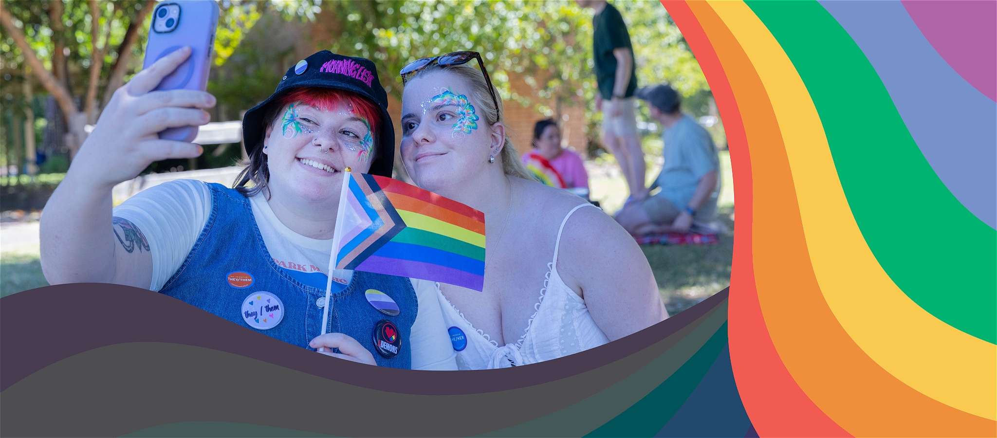 Two people smiling lovingly while taking a selfie with progress pride flag