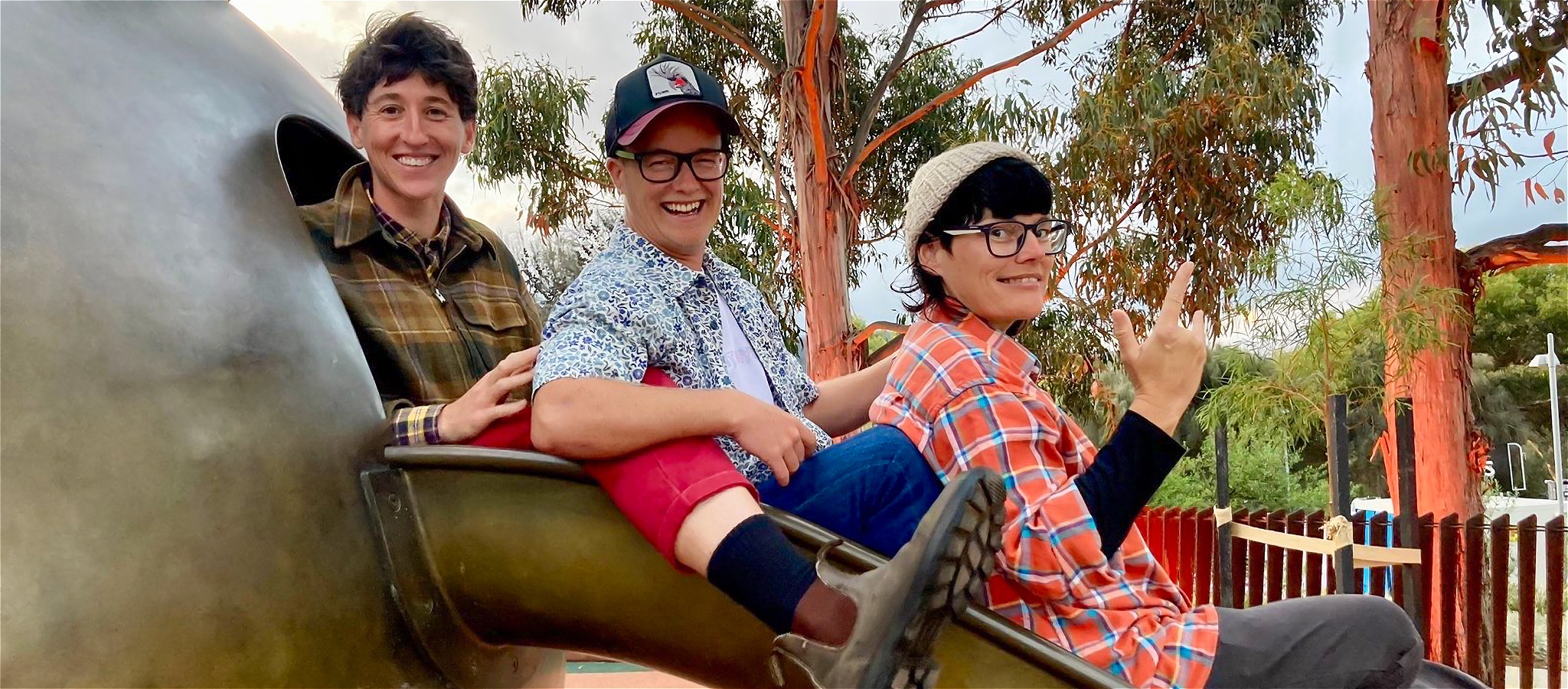 Three band members on a slide in a park.
