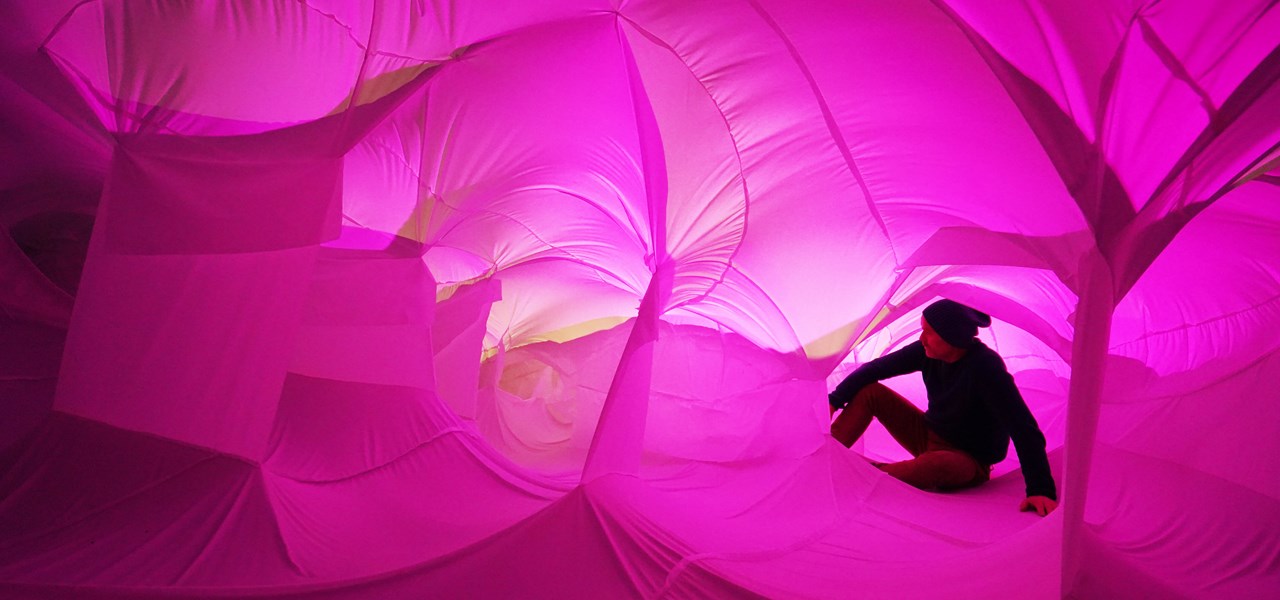 A person seated inside a pink-toned canvas structure