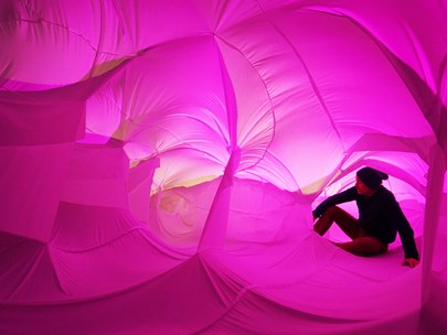 A person seated inside a pink-toned canvas structure
