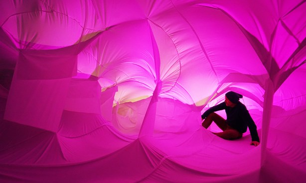 A person seated inside a pink-toned canvas structure