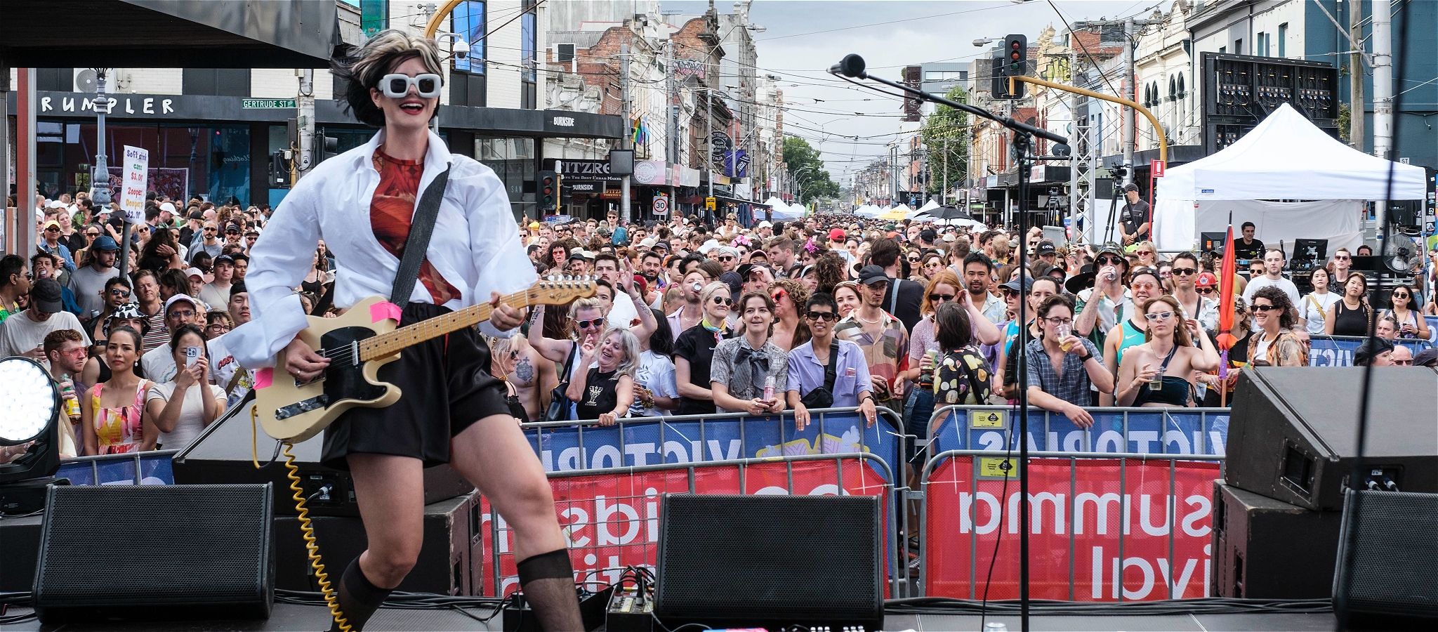 Performer on stage in front of a large street crowd dancing