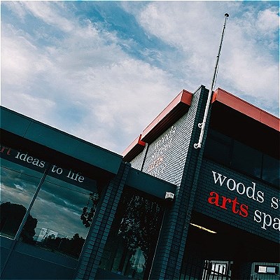 Exterior of the Woods Street Arts Space looking skyward toward a flagpole with no flag