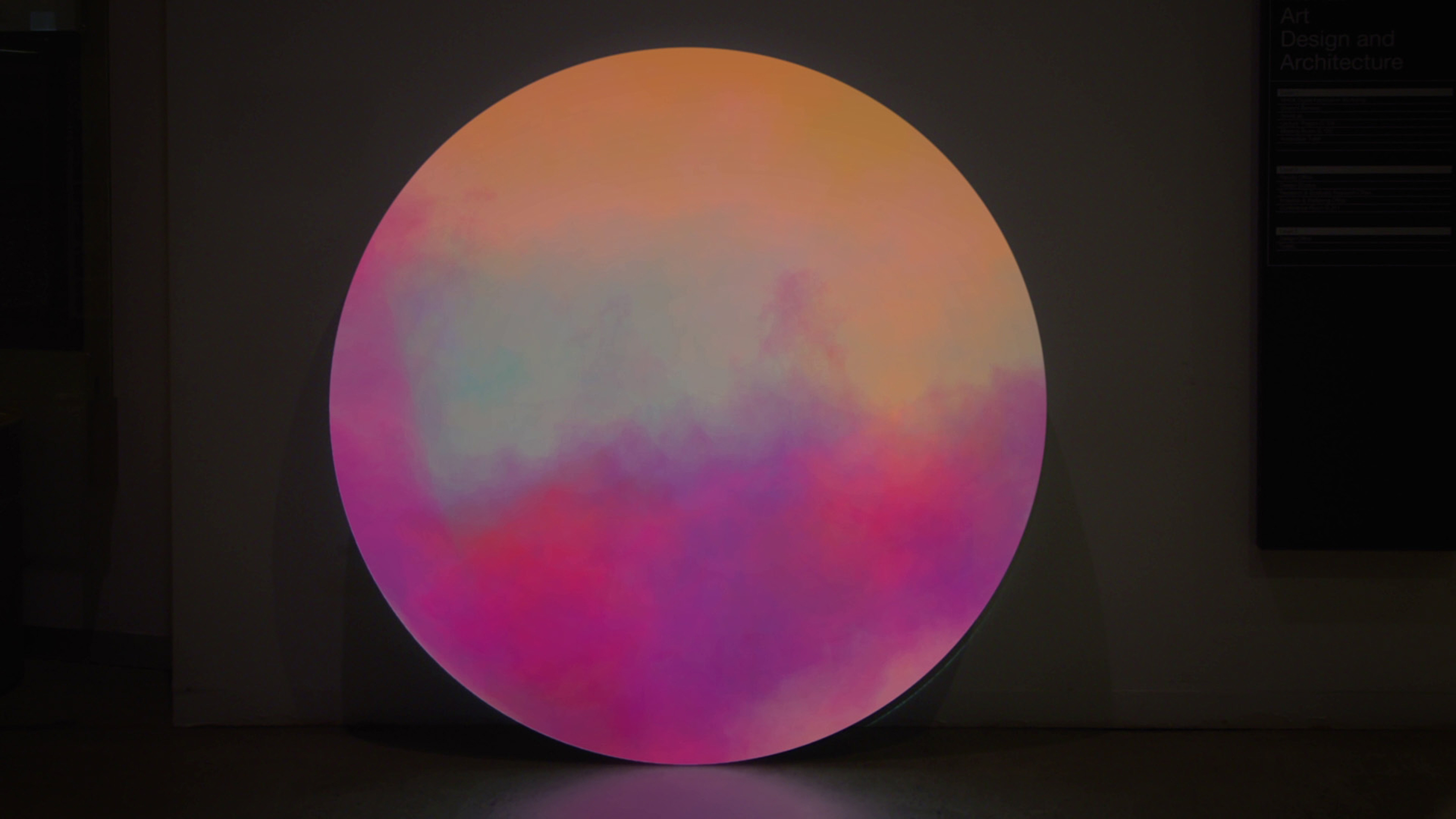 A sphere (perhaps representing planet Earth) in brown, red and mauve hues against a black background