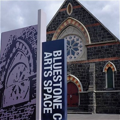 A church with a large circular window on the top floor. A sign shows the venue name,