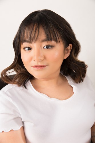A headshot of Crystal, who has wavy brown hair and is wearing a white top.
