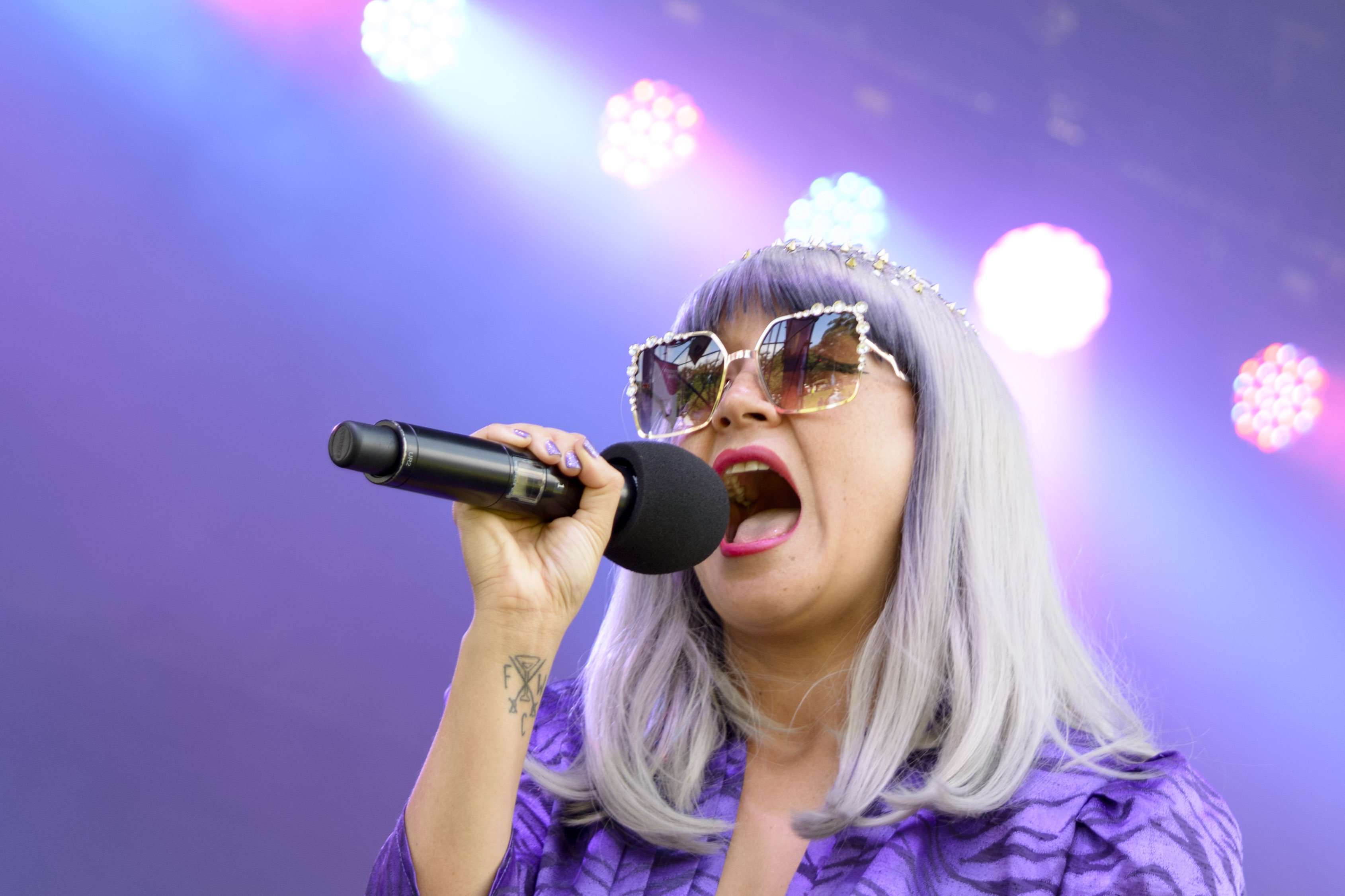 Women with grey hair singing into a microphone - mauve lighting