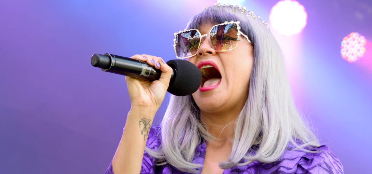 Women with grey hair singing into a microphone - mauve lighting