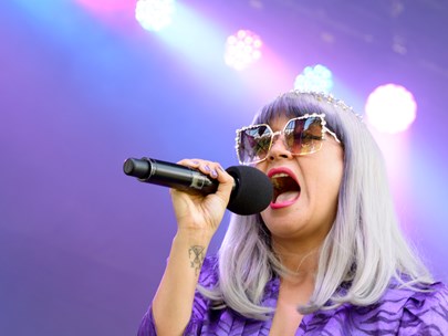 Women with grey hair singing into a microphone - mauve lighting