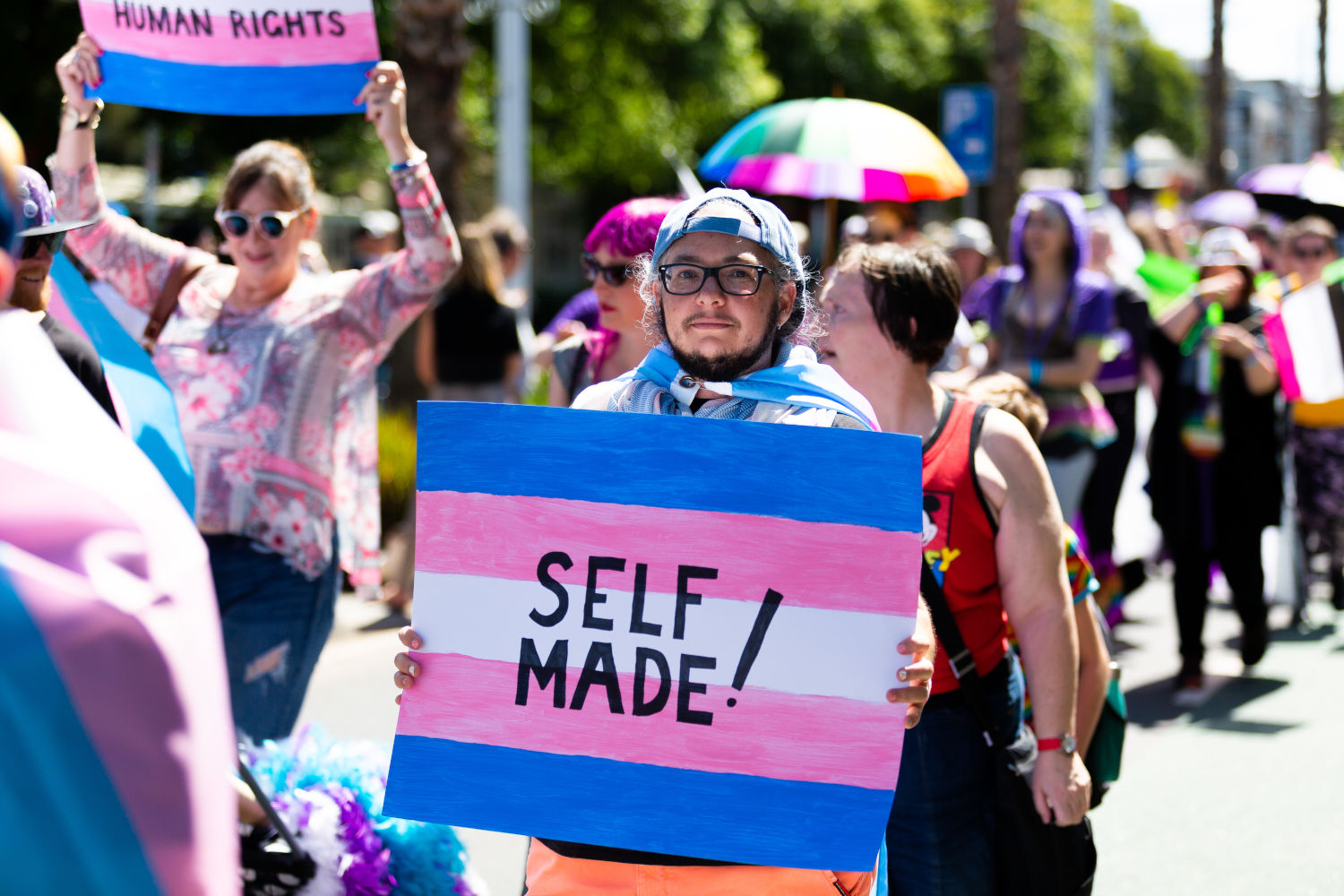 People marching at Pride March. The first person is holding a banner: "Self made!"