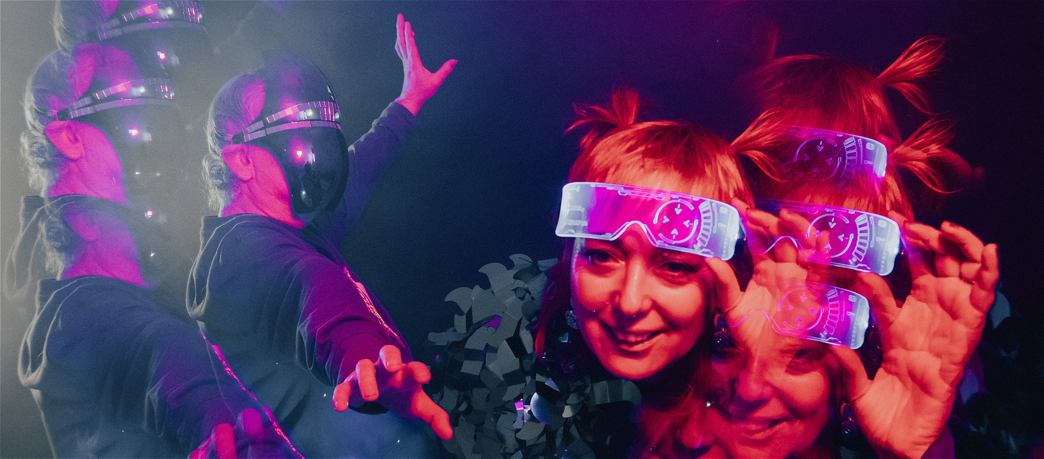 person in robot mask waving arms person peering under cyber glasses leaning forward smiling with VFX