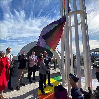 People looking at a flag being hoisted on the Victorian Pride Centre rooftop