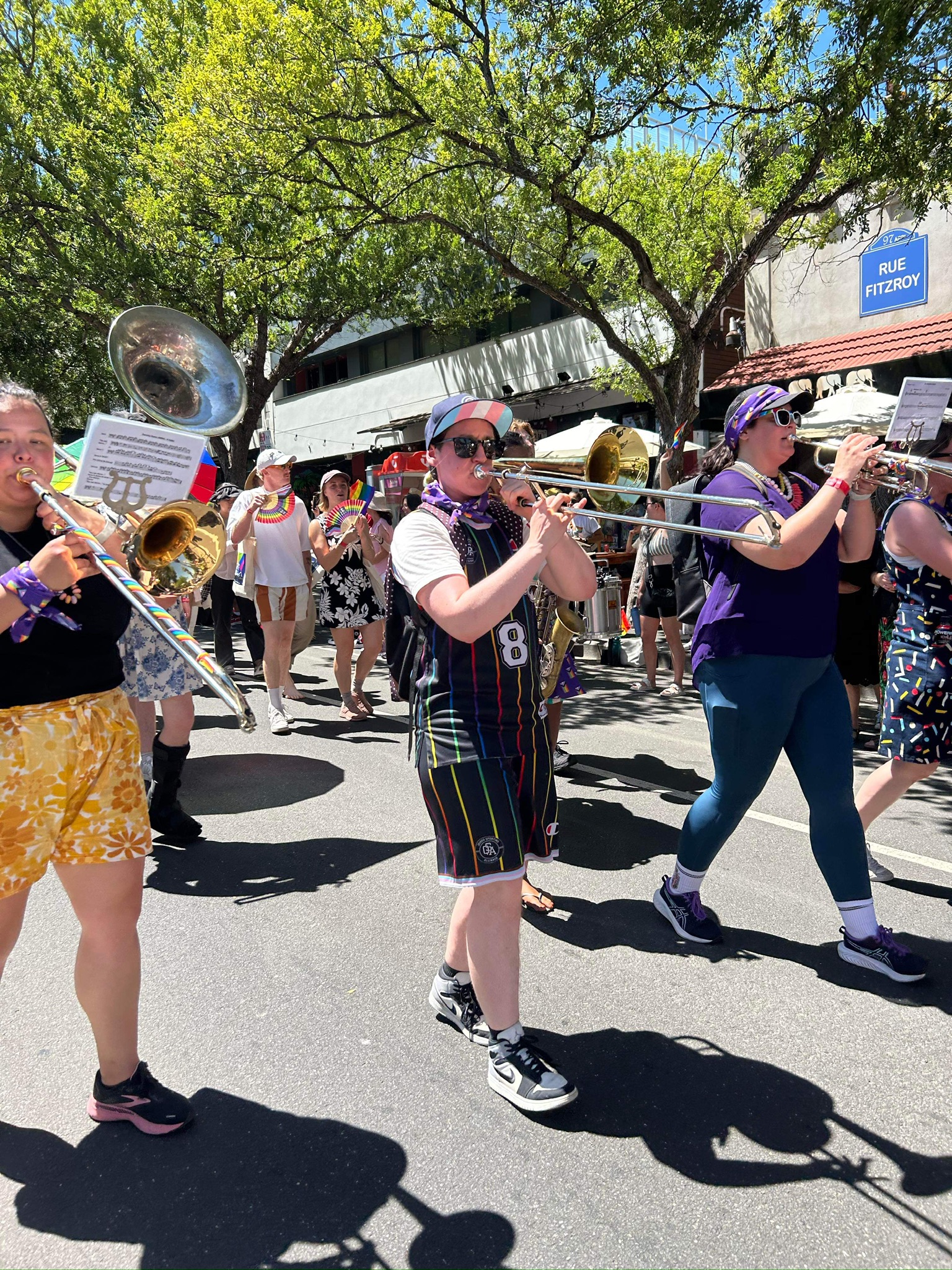Three people marching down the street while playing wind instruments