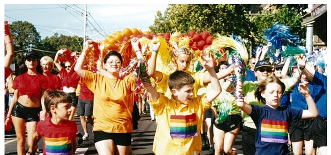 Pride March 2000 image: some kids marching, with bright red and gold decorations behind them