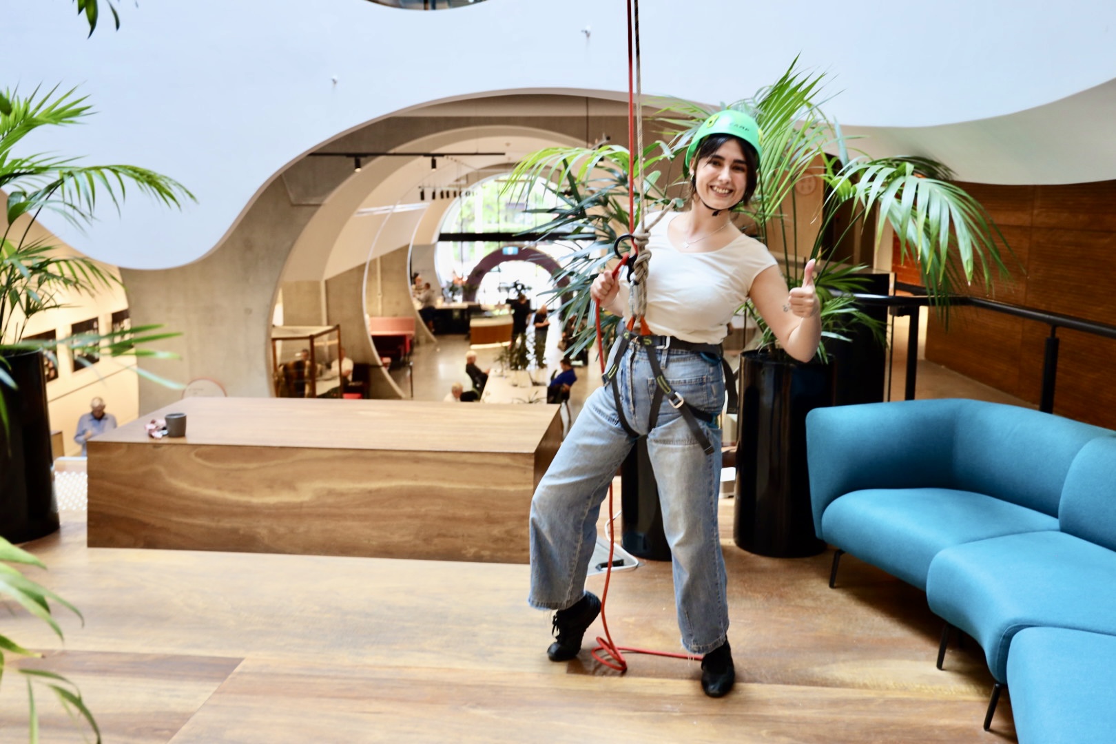 An image of a person in a harness having just abseiled down the atrium of the Victorian Pride Centre