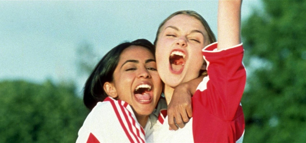 Two teenagers in red and white football jerseys celebrate the scoring of a goal.