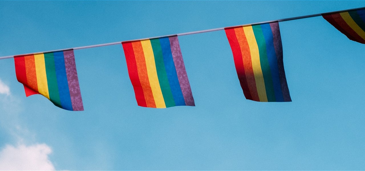 Rainbow bunting on a blue sky background with a hint of wispy white clouds