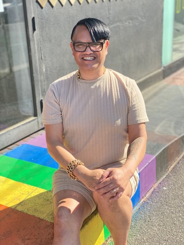 Richard sitting on a rainbow-coloured door mat