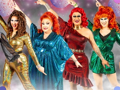 A colourful drag queen line-up on a stage. Each has their arms outstretched.