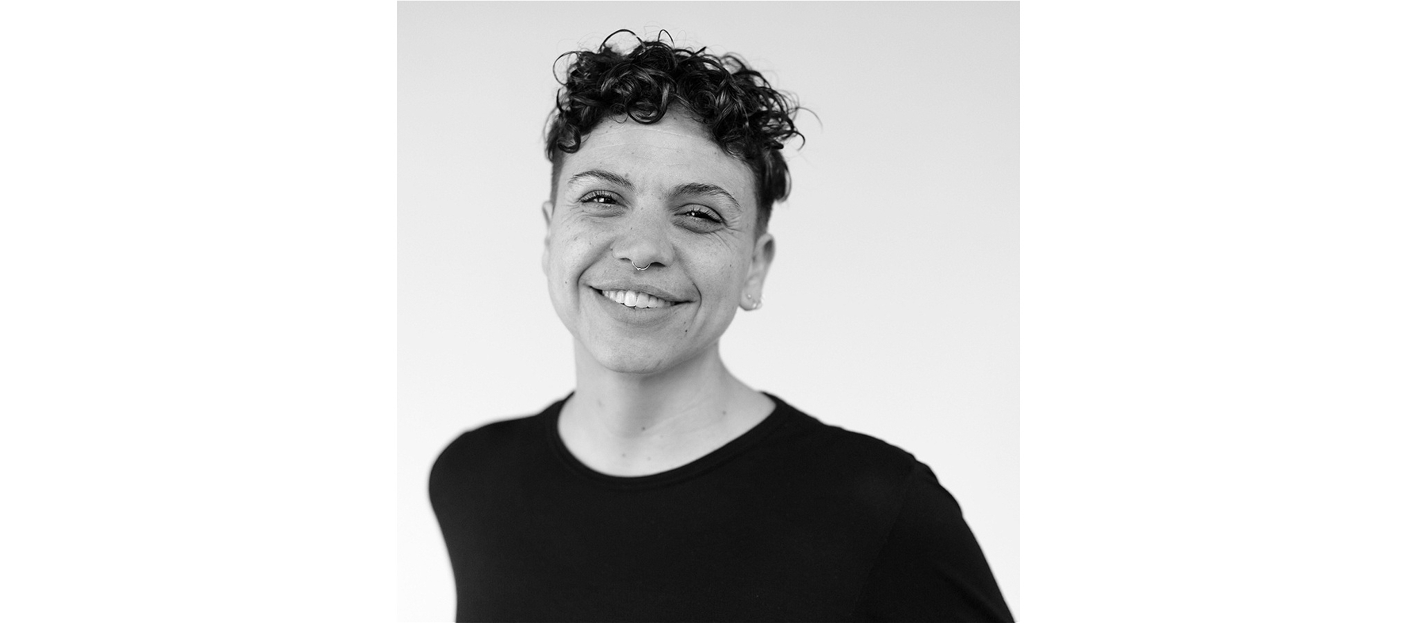 A person smiling and wearing a dark coloured t-shirt