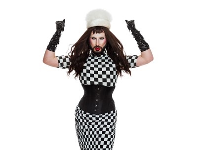 Silk dressed in checkerboard black and white dress, gloves and white hat sporting long hair and a beard
