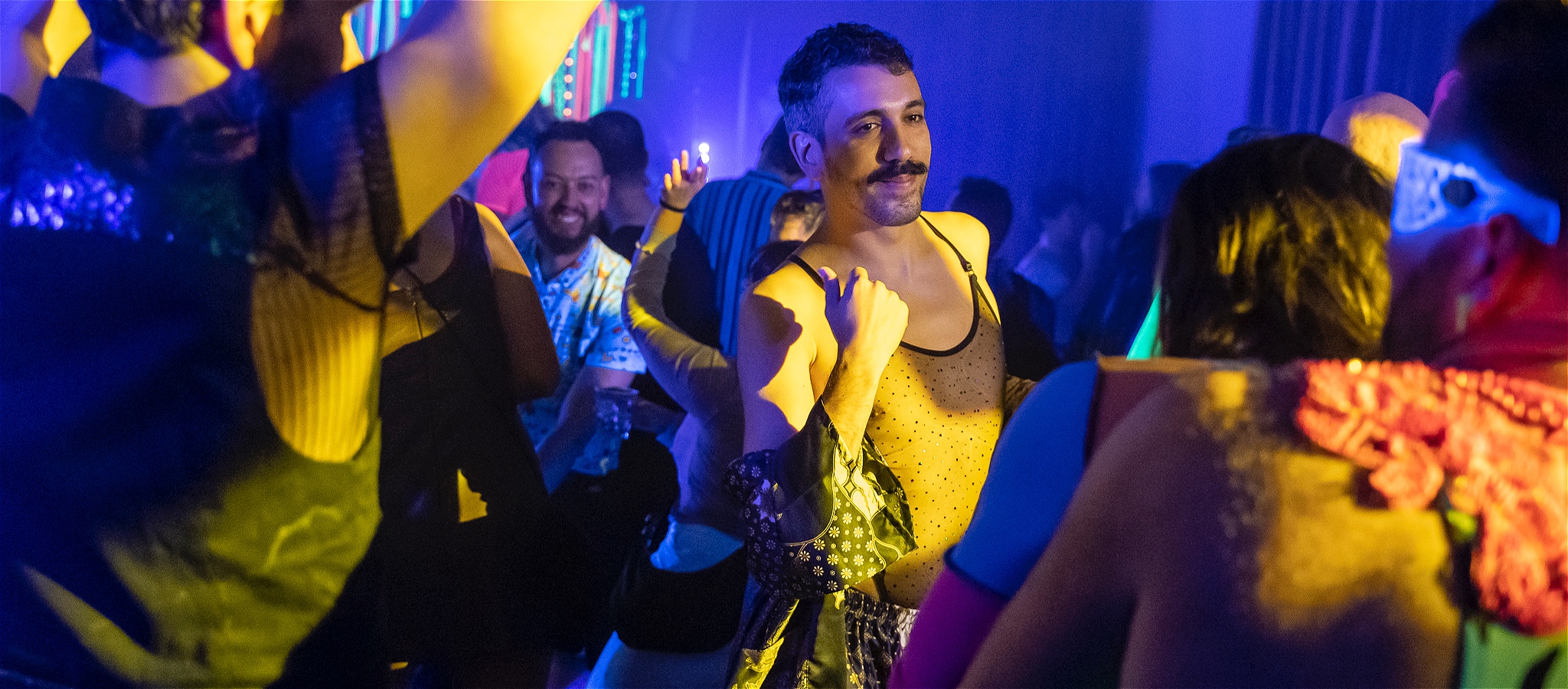 A dance floor filled with colourful people lost in a moment dancing