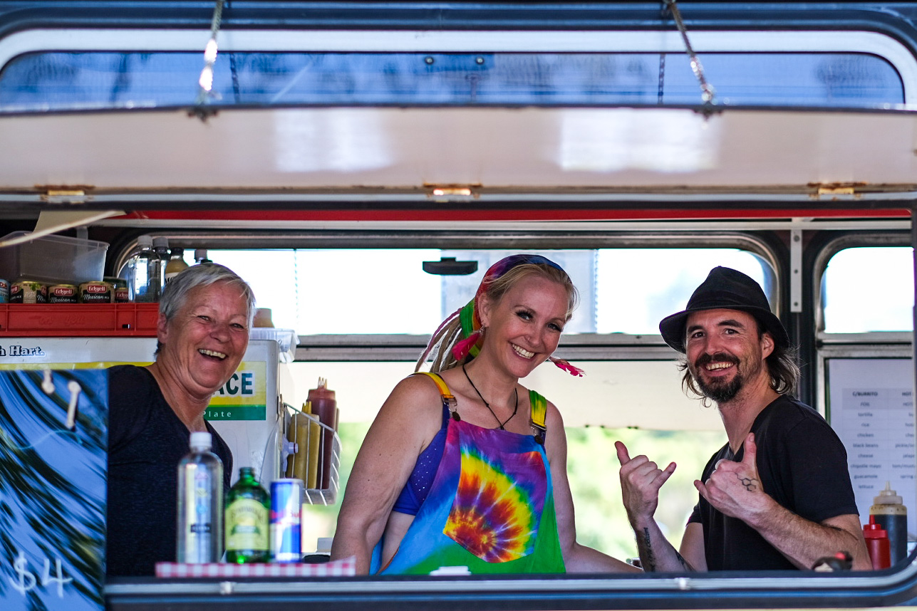 Three happy looking people behind the counter of a food van