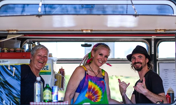 Three happy looking people behind the counter of a food van
