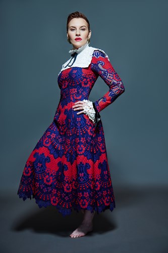 Photo of Kate dressed in a Flamenco style dress standing barefoot, looking defiantly at the camera, hands on hips
