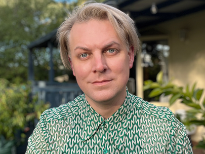 A person with blond hair wearing a green button down.