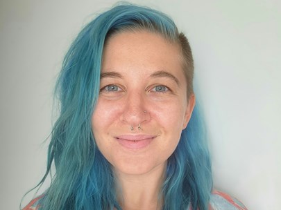 A person with long blue hair smiling.