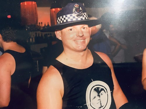 Will Walton cheekily wearing a singlet and the hat of a policeman