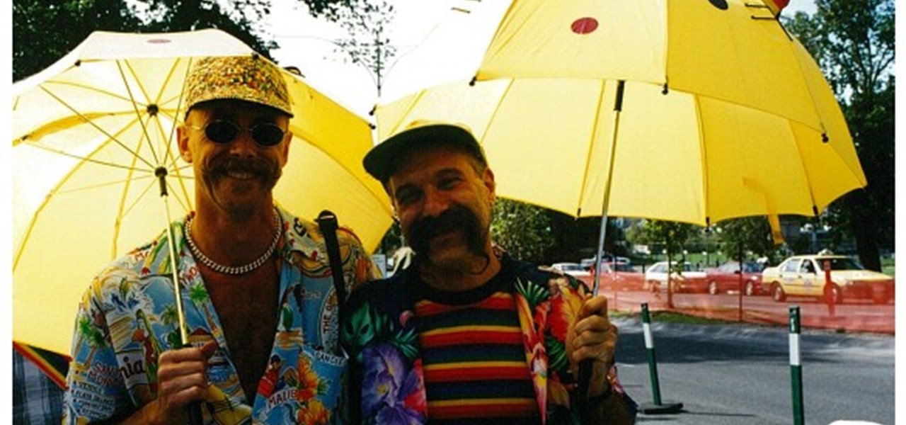 Pride March 2000 image: a happy looking gay male couple under yellow umbrellas