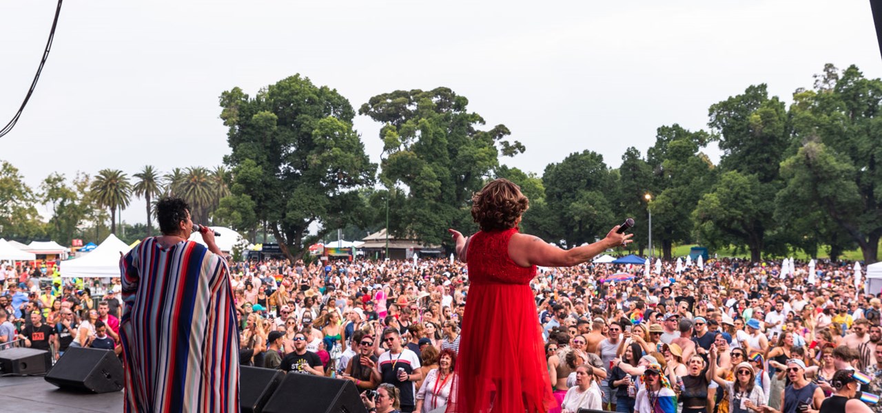 Two people on stage at Midsumma Carnival (one is Dolly Diamond), large crowd in background