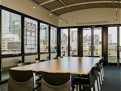 View of interior of the Wayi Djerring room, with large table and chairs and the CBD skyline behind