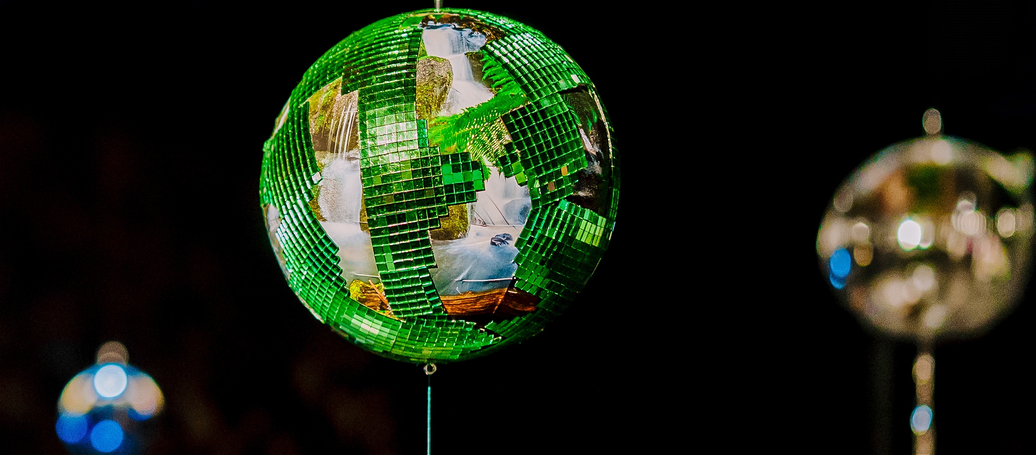 A motley green-shades mirror ball against a black background