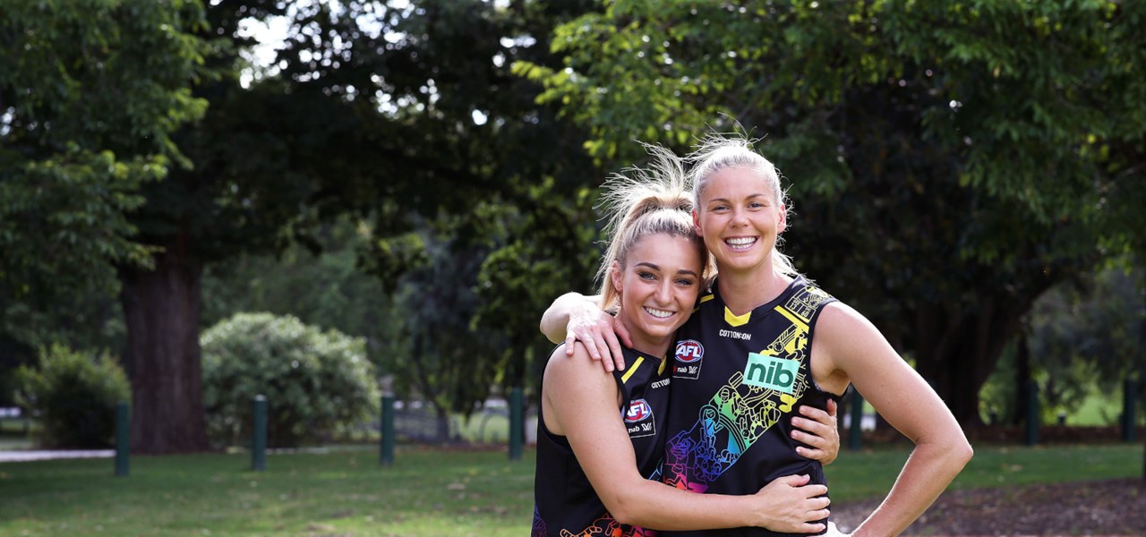 Two female AFL players hugging each other in a public park
