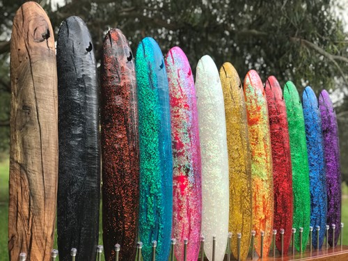 Sculpture consisting of a row of vertical poles, rounded at the top, painted in rainbow colours