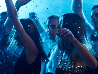 Multiple people dancing at a nightclub, with confetti/glitter falling from ceiling, with blue haze effect.