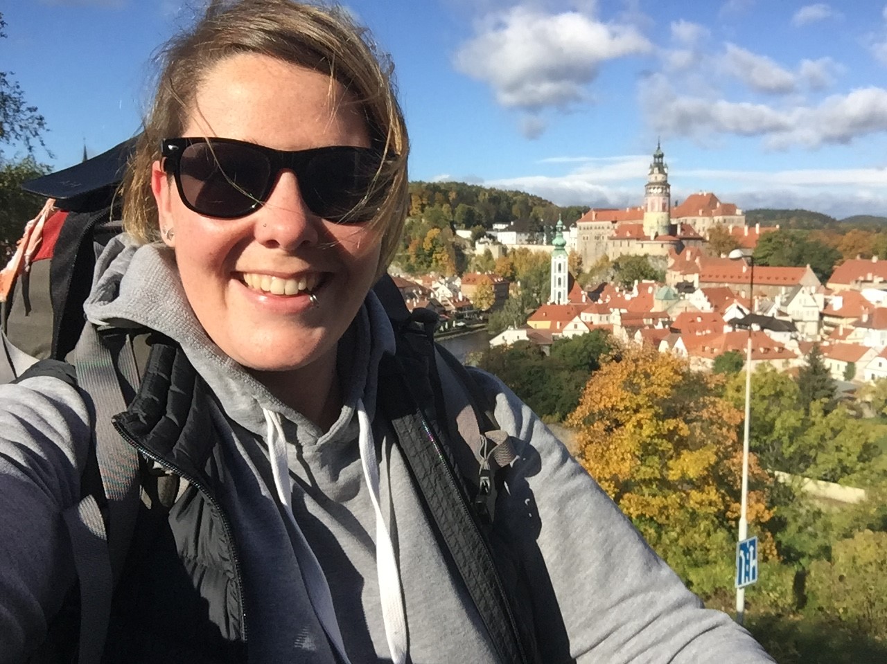 Photo of Ash, seemingly on a walking track with a medieval, European-looking village in the background