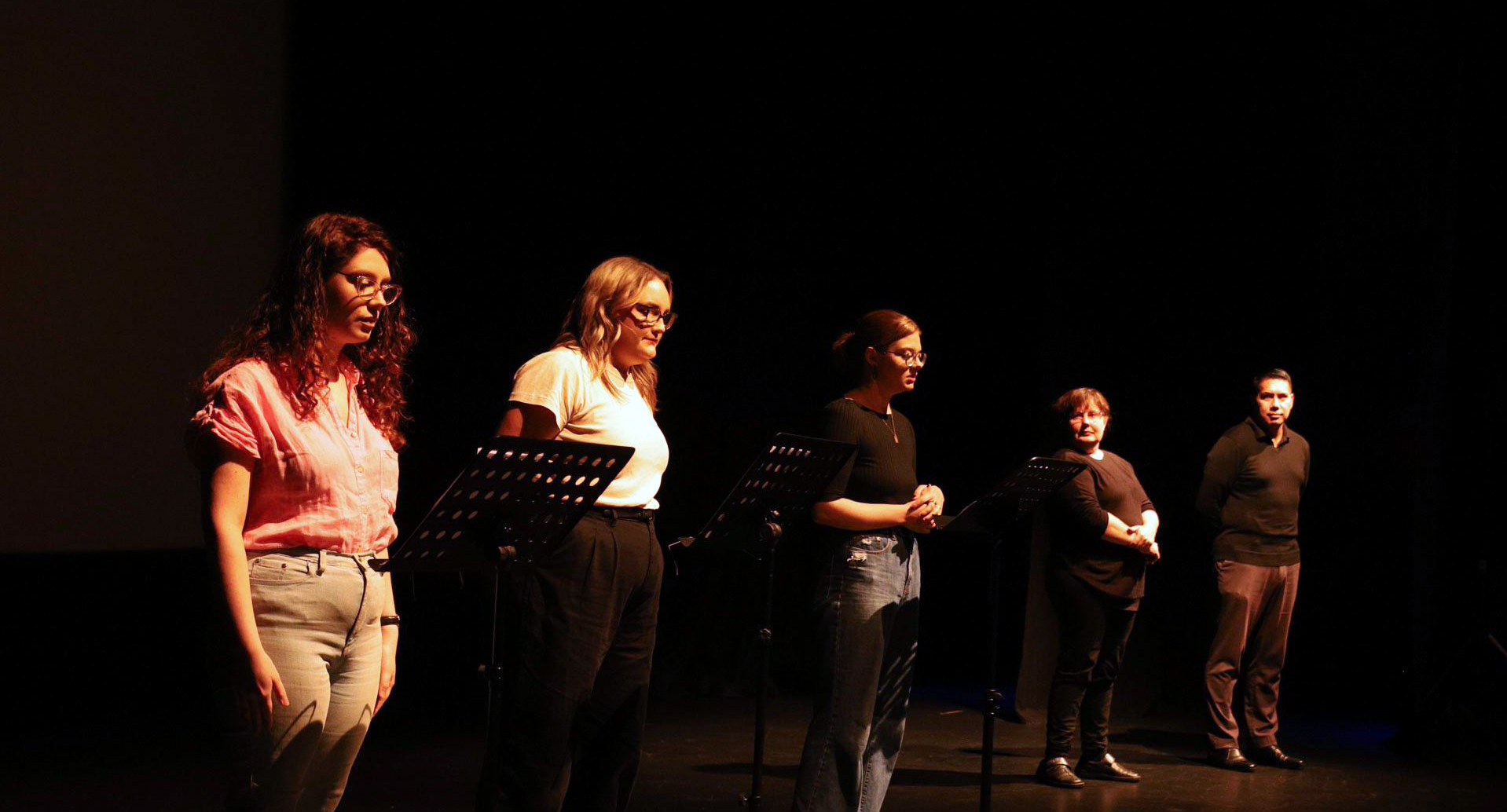 Five people standing on stage, one of them in front of a lectern