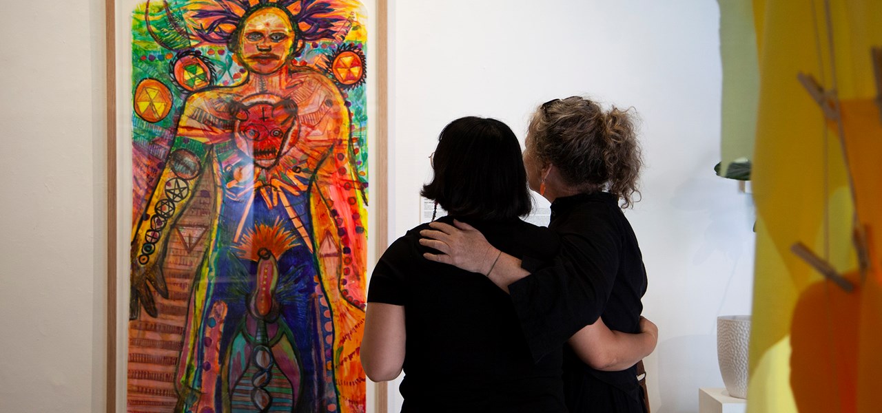 Two people looking at artwork, with arms around each other