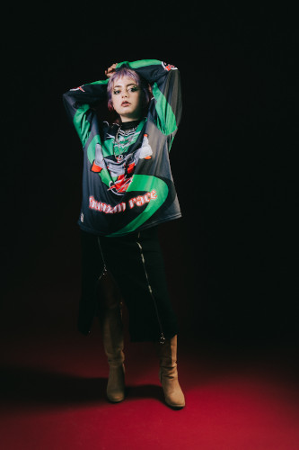 Chico holding their arms above their head while standing on a stage-like space