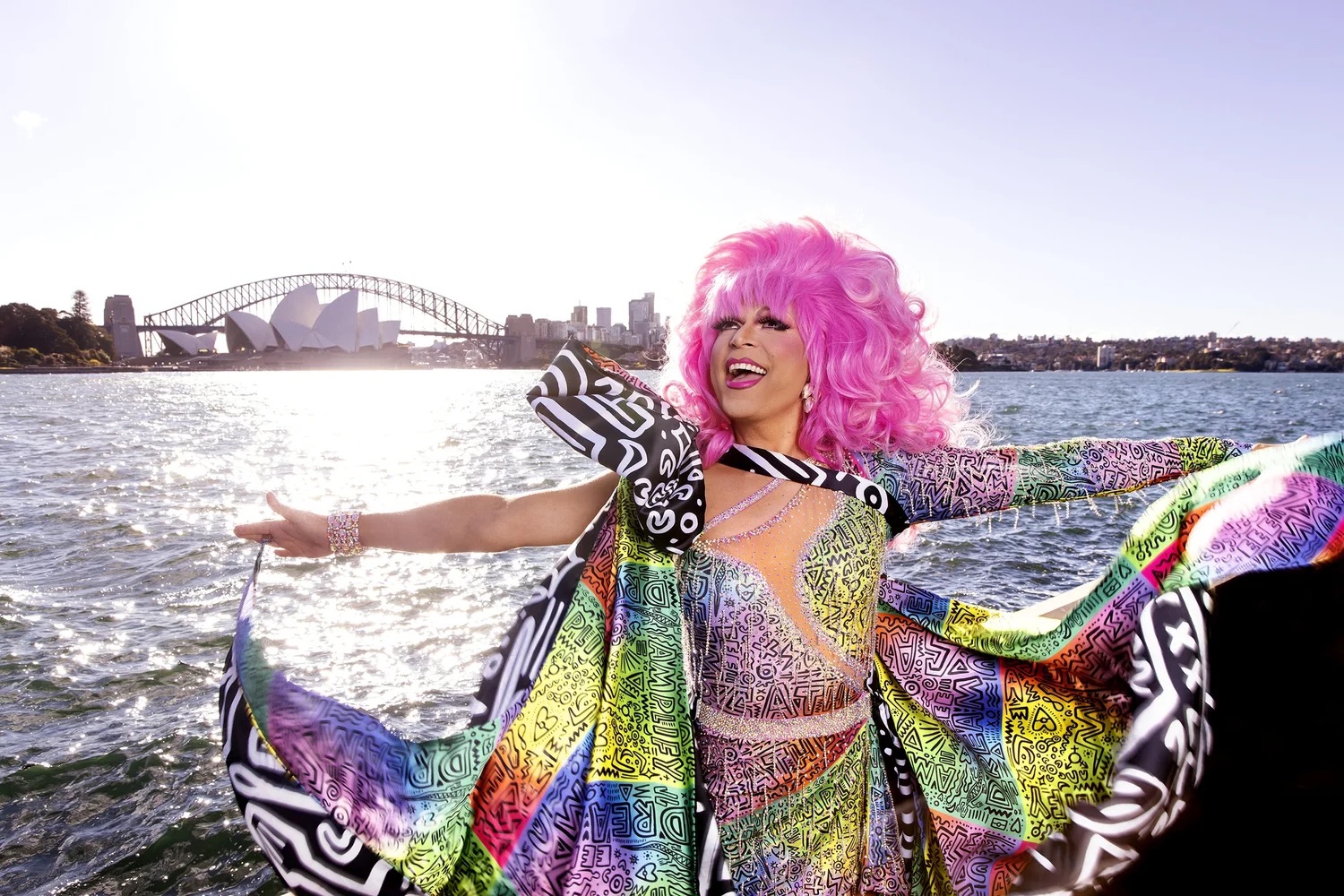 Miss Ellaneous dressed in a glamorous gown while on a boat with the Sydney Opera House and Harbour Bridge in the background