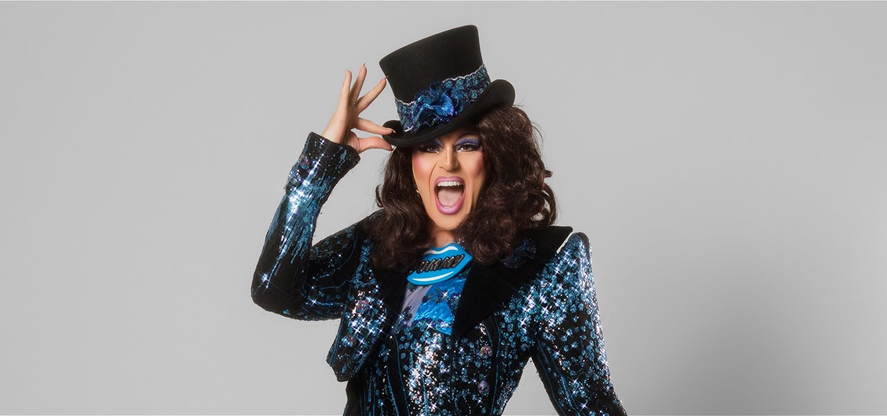 Valerie Hex wears a sparkly suit and is posing with a top hat.