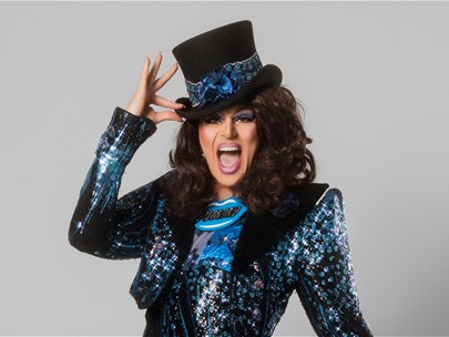 Valerie Hex wears a sparkly suit and is posing with a top hat.